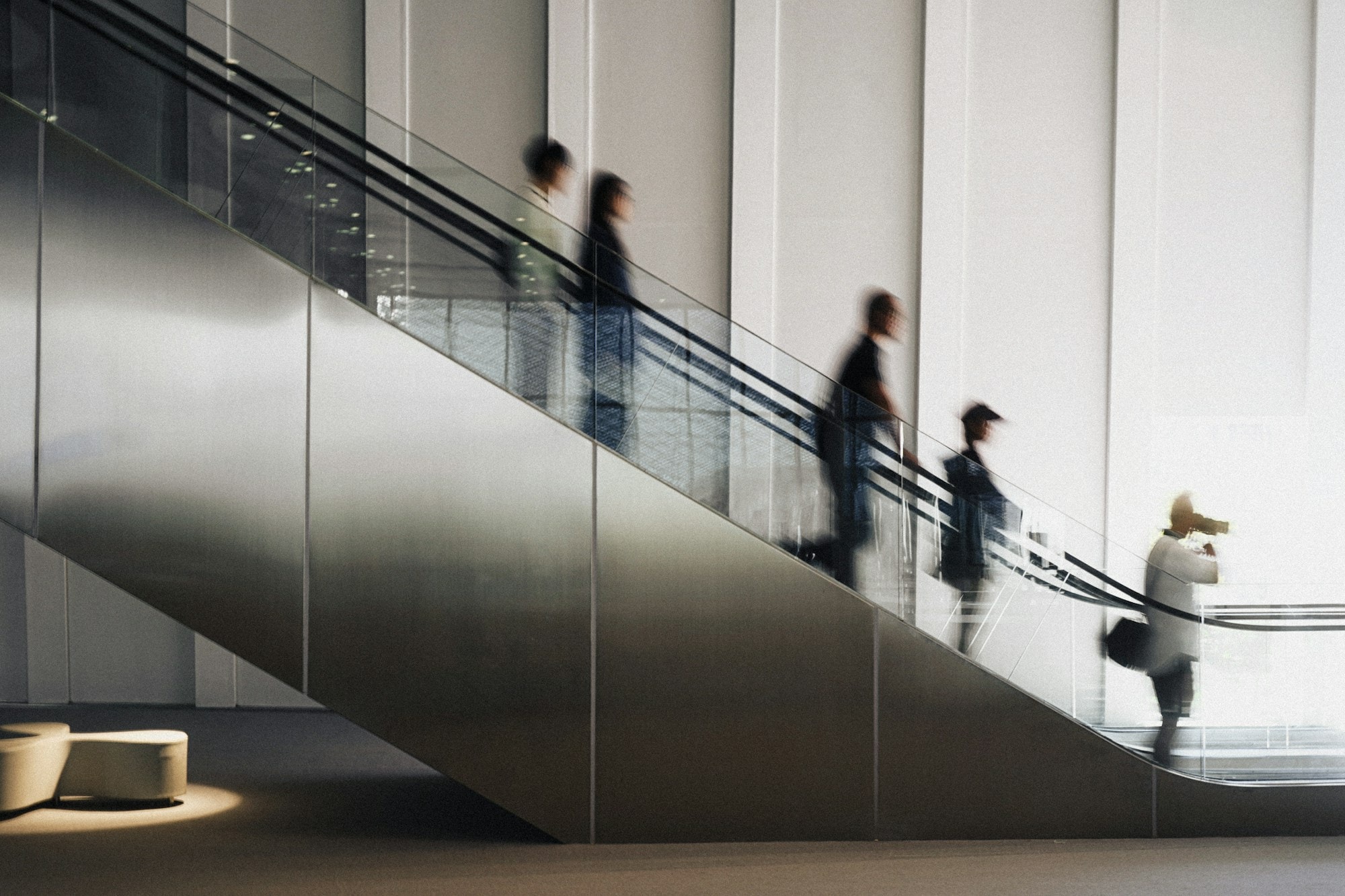 Blurred figures riding a modern escalator in a corporate interior
