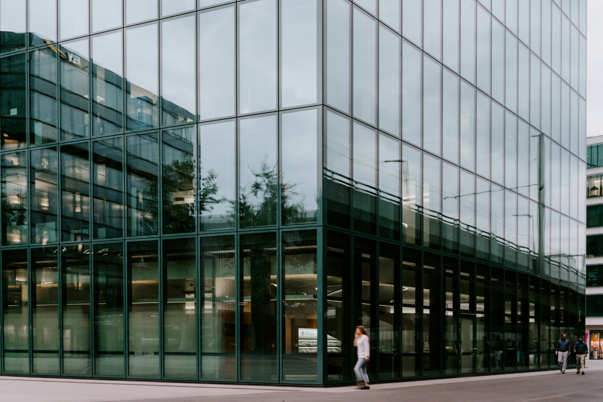 A person walking along the glass facade of a modern office building